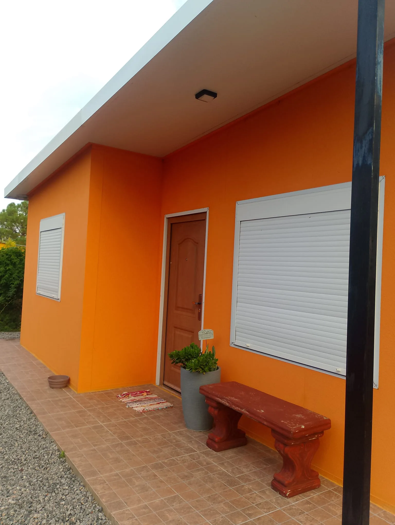 Casa de isopanel color terracota, galería cubierta y jardín.