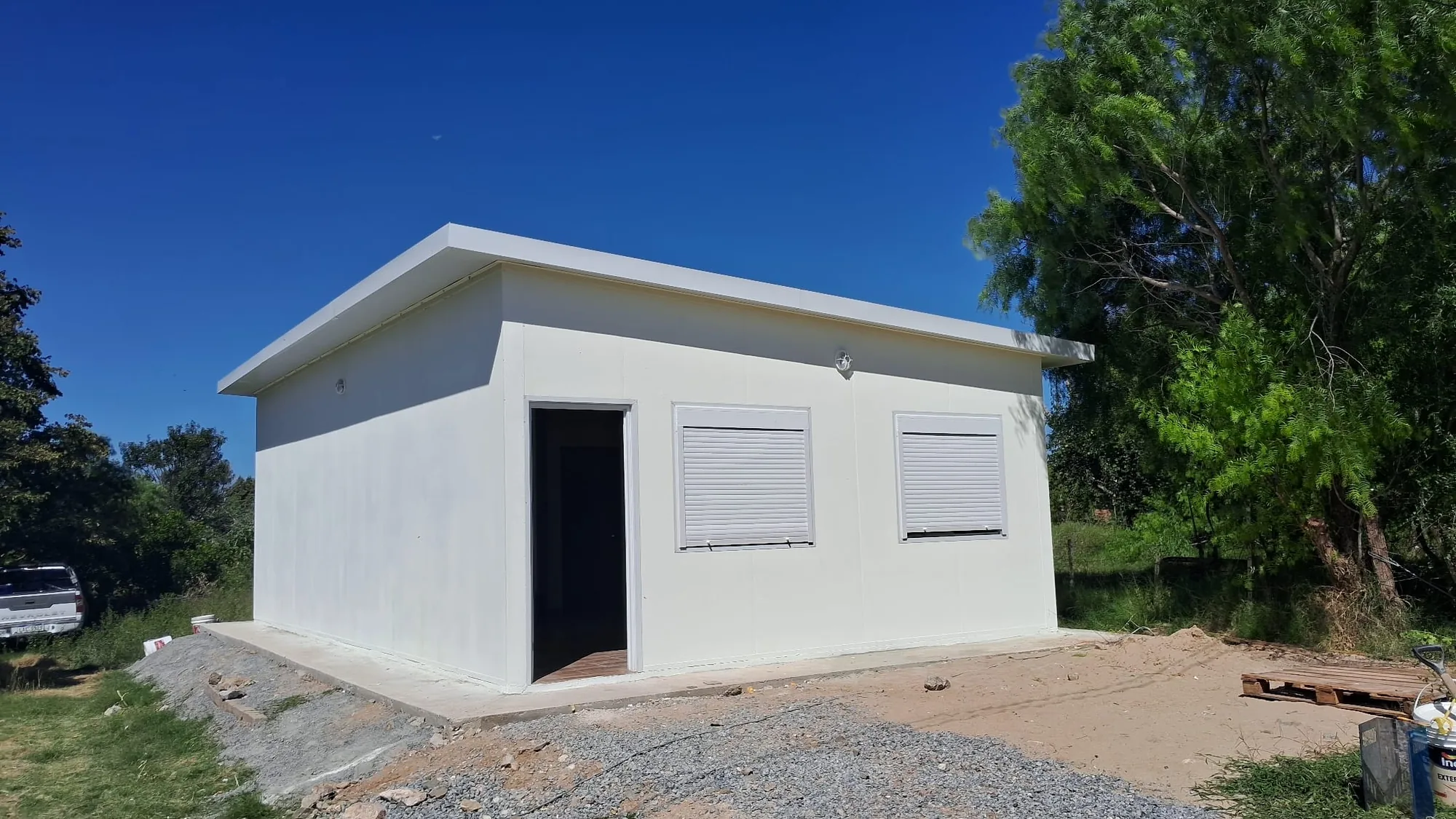 Casa de isopanel blanca de líneas rectas y amplio parque.