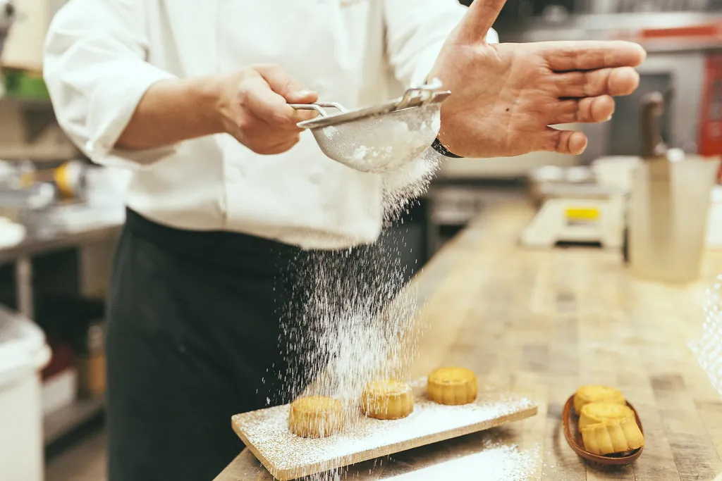 Manos de pastelera artesanal amasando en el obrador de IKARA